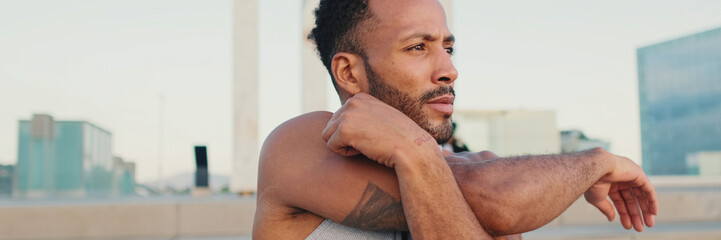 Obraz premium Young bearded male athlete jumps and makes movements with his hands during workout on the waterfront