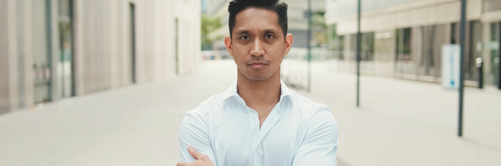 Naklejka premium Young businessman looking at camera while standing in business district
