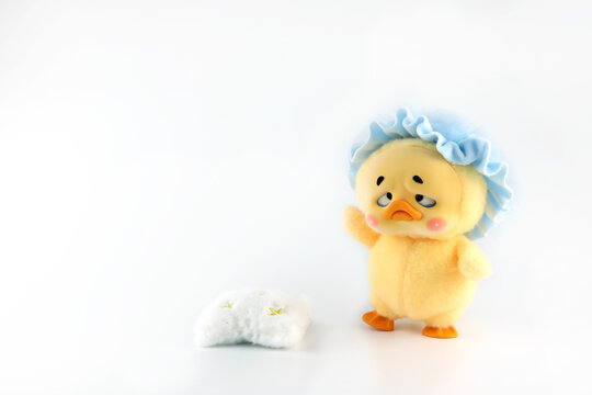 a cute art toy doll name Upsetduck , a cute fluffy yellow duck in blind box or mystery box from China SJD brand, display isolated on white shelf background with pillow prop in art toy shop