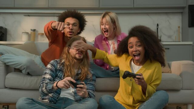 African American woman girl cheating playing console video game win close eyes to Caucasian man male guy failure lost angry friends buddies support four people high five weekend fun home competition