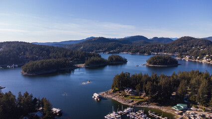 Aerial view of Gerrans Bay. Forested Islands sit in the water. Rolling mountains stretch along the horizon 