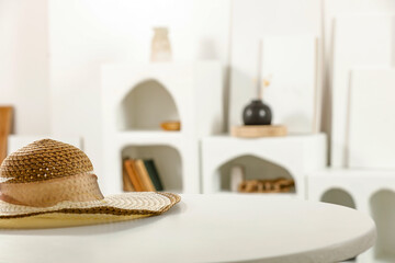 Summer hat on wooden table and white home interior with natural light. 