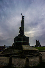 Obraz premium The World war memorial at Aberystwyth at dawn, with the ruins of the medieval Castle in the Background
