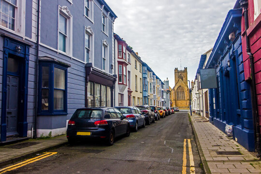 Vibrant colourful apartments lining a street leading towards a stone church in Aberystwyth a coastal town in West Wales
