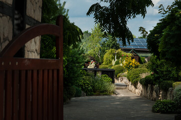 Fototapeta premium entrance to the yard with a beautiful landscape design, cascades of colored bushes and flowers
