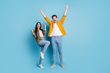Full size photo of two nice young partners raise fists empty space wear shirt isolated on blue...