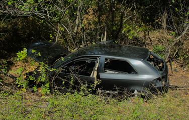 A wrecked car on the roadside in a forest. A vehicle after a road accident.