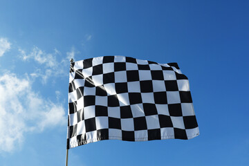 Checkered flag against blue sky outdoors, low angle view