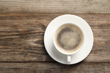 Tasty coffee in cup on wooden table, top view. Space for text