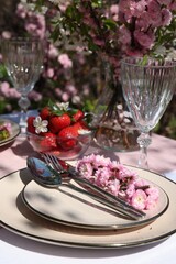 Stylish table setting with beautiful spring flowers in garden