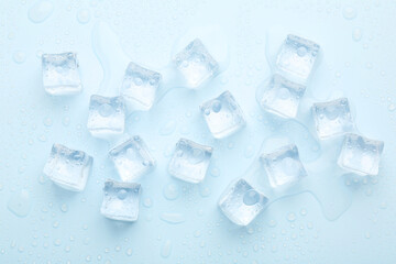 Crystal clear ice cubes on light blue background, flat lay