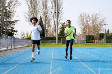 Obraz premium Two african men running on a track, one in a green shirt