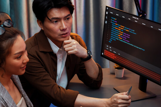 IT developers discussing with point to intelligent website development coder system running data online two screens information technology at neon light room at modern office. Infobahn.