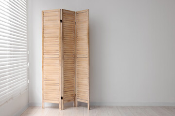 Wooden folding screen near white wall indoors, space for text