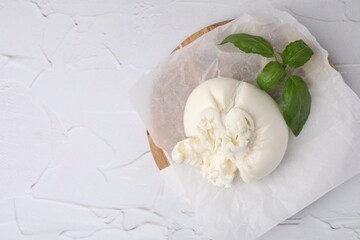 Delicious fresh burrata cheese with basil leaves on white textured table, top view. Space for text