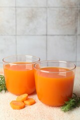 Healthy carrot juice in glasses and fresh vegetable on color textured table