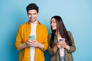 Photo of funky cool couple dressed shirt texting modern device emtpy space isolated blue color...