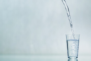 A glass beaker is filled with water. The process of filling a glass with water