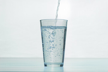 A glass beaker is filled with water. The process of filling a glass with water