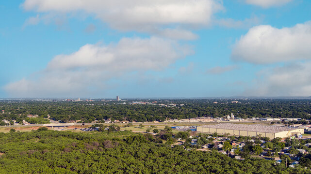 Aerial establishing shot of Abilene Texas downtown cityscape with skyscrapers in the background traffic on the roads and a blue sky.