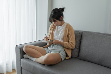 Asian Business woman working from office taking reading and writing notes in note pad