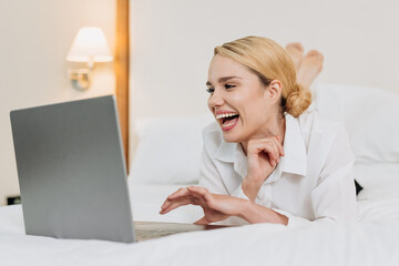 Blonde business woman works in the evening in a hotel room during a business trip. Work-life balance, leisure and corporate travel.
