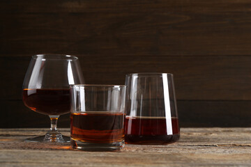 Different delicious liqueurs in glasses on wooden table