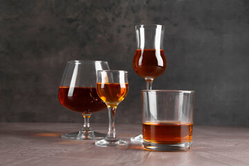 Many different liqueurs in glasses on grey textured table