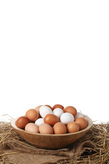 Fresh chicken eggs in bowl and dried straw on table against white background