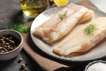 Pieces of raw cod fish, dill and peppercorns on table, closeup