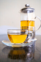 Green Tea in a Glass Tea Cup and Saucer with French Press teapot on side
