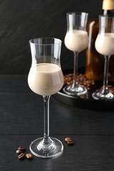 Coffee cream liqueur in glasses and beans on black wooden table