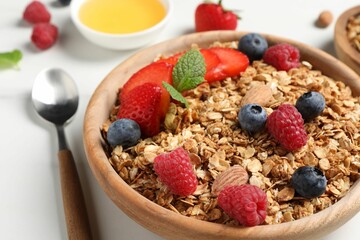 Tasty granola with berries, nuts and mint on white table