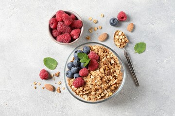Tasty granola with berries, nuts and mint on grey table, flat lay