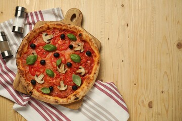 Delicious pizza with tomatoes, mushrooms, black olives and basil on wooden table, top view. Space for text