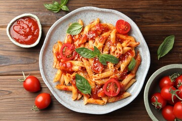 Delicious pasta with tomato sauce, basil and cheese on wooden table, flat lay