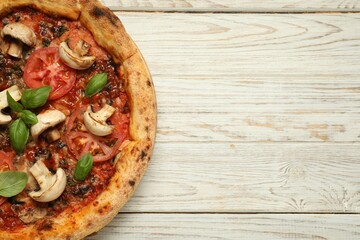 Tasty pizza with basil, mushrooms and tomato on wooden rustic table, top view. Space for text