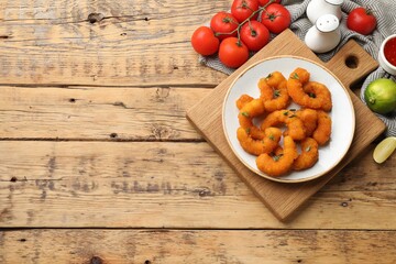 Tasty breaded fried shrimps served on wooden table, flat lay. Space for text