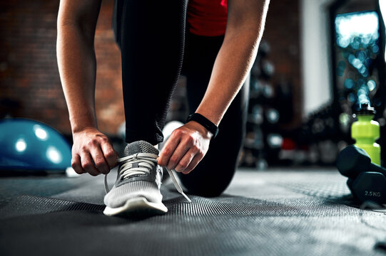 Runner, hands and tying shoes for training, fitness and exercise or running with sneakers, fashion and getting ready. Person or athlete with laces and legs or feet for cardio, health and wellness gym - Powered by Adobe