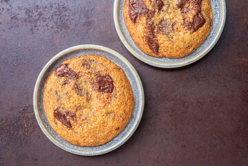 Homemade chocolate chip cookies in ceramic plates on rustic background.