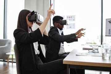 Business professionals using virtual reality technology during meeting in modern office. Colleagues explore VR applications for work. Focus on innovation, technology, and teamwork.