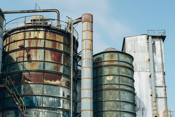 Factory chimneys and silos emitting smoke, representing industrial production and its environmental impact. Industrial landscape