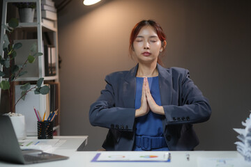 Businesswoman practicing meditation at her office desk, fostering a calm and focused work environment. Maintaining work-life balance.