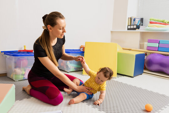 Physiotherapist testing little baby for presence of reflexes and assessing health using arm traction test. Hypotonia in babies with damage to CNS
