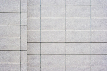 Close up of a tiled wall with a grid pattern, featuring light gray tiles and dark grout lines, as texture, background.