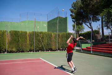 Fototapeta premium Young tennis player serving the ball on outdoor court