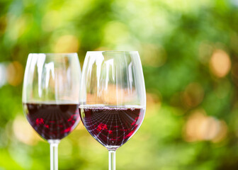 Two wine glasses with red wine and a beautiful bokeh on the background. The focus is on the reflection in the wine glass. Shallow depth of field. Copy space.