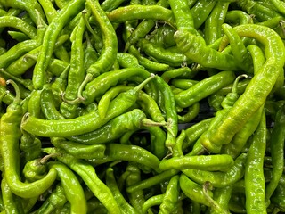 A close-up of a large pile of fresh green chili peppers