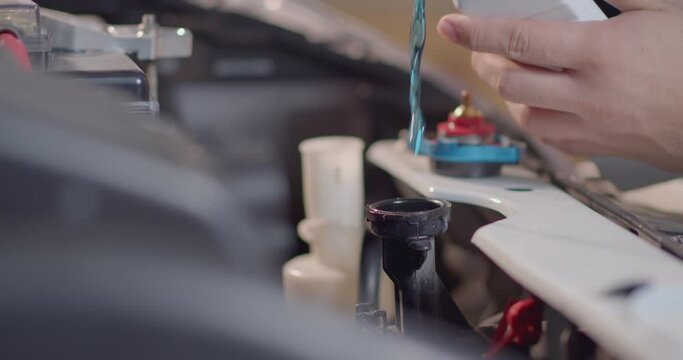 The blue radiator water.Adding Coolant to Car radiators or Pouring antifreeze to the car radiator.The mechanic pours the cooling fluid into the radiator spure.Adding liquid to the car's radiator.