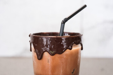 A cup of chocolate drink with a straw in it